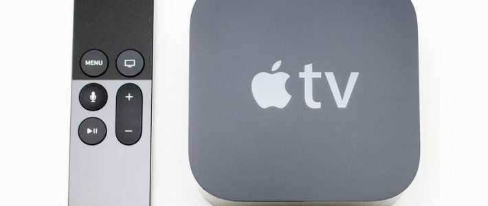 Paris, France - November 10, 2015: New Apple TV media streaming  player microconsole by Apple Computers next to the new touch remote swipe-to-select with integrated Siri and motion sensor on white