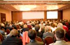 Rear view of many listeners sitting on chairs during lecture at conference
