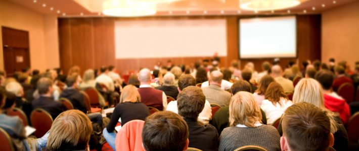 Rear view of many listeners sitting on chairs during lecture at conference